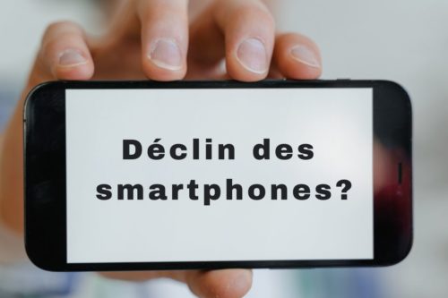 Mains tenant un smartphone affichant le texte "Déclin des smartphones?"